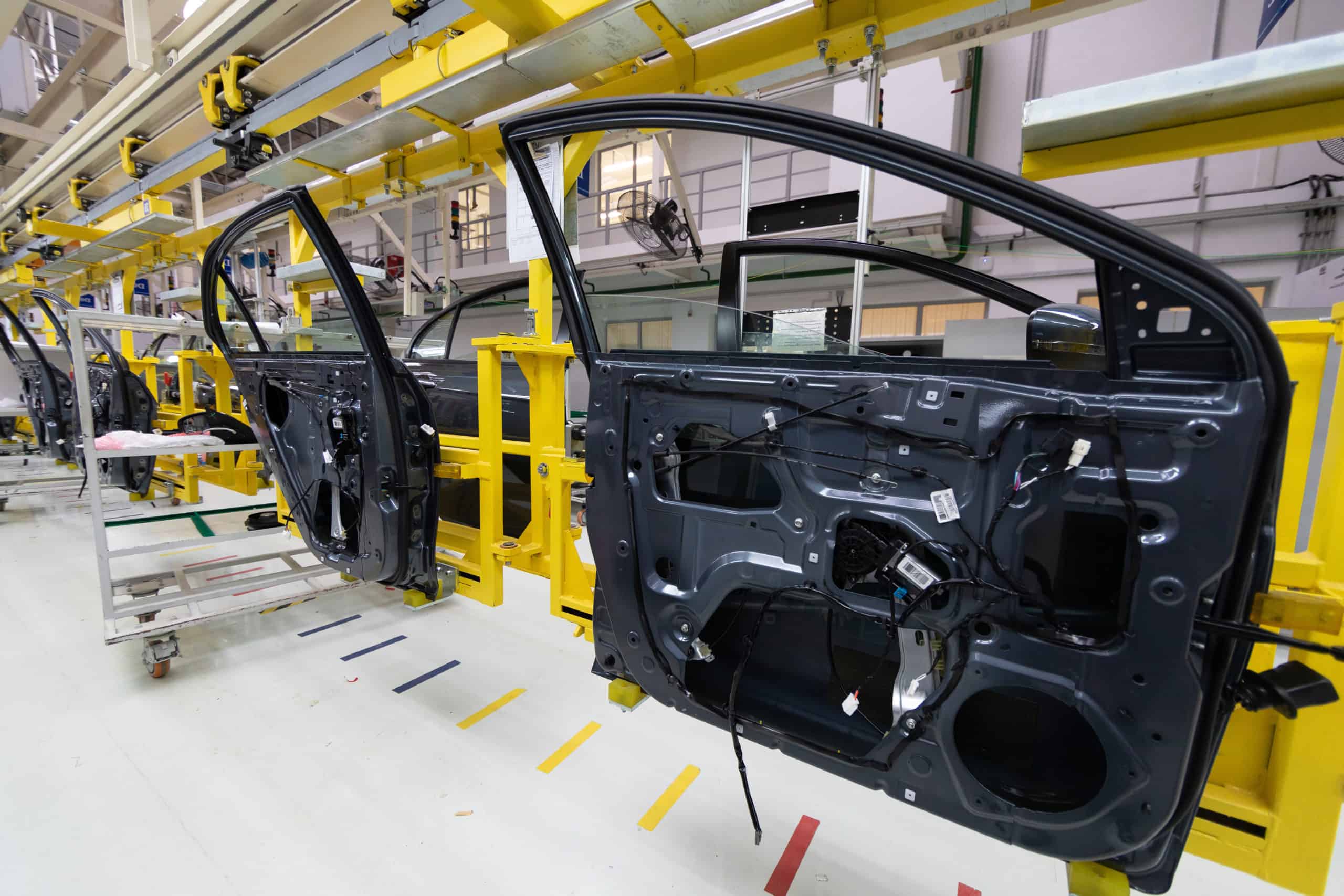 Automotive body doors moving through a standardized assembly line inside a modern vehicle manufacturing plant.