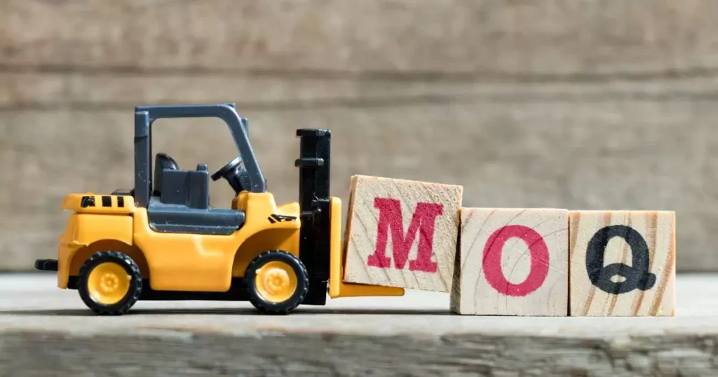 A small forklift model moving wooden blocks labeled MOQ on a neutral surface.