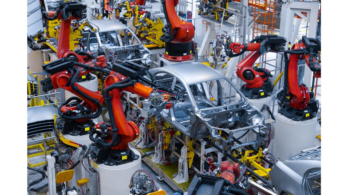 Automated automotive body assembly line with multiple industrial robotic arms welding car body frames in a factory environment